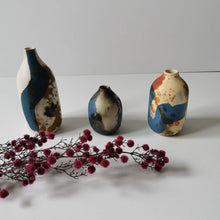 Charger l&#39;image dans la galerie, Petit soliflore en porcelaine enfumée, tâches bleues et rouilles (oxyde de cobalt et de cuivre)  Ce vase est empreint d&#39;une profondeur et d&#39;une force spirituelle sacrée obtenus grâce à la technique ancestrale de l&#39;enfumage.   Brut, délicat et intemporel, ce vase se suffira à lui-même pourra accueillir vos plus belles branches de fleurs séchées ou de fleurs fraiches.   Le principe de l&#39;accumulation est tendance, nous vous conseillons de le marier avec les autres soliflores de Raisa Salvador. 
