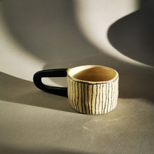 Charger l&#39;image dans la galerie, Magnifique tasse à grande anse noire, elle pourra vous servir à boire votre thé ou café et pourquoi pas comme objet de déco sur vos étagères.  La fonctionnalité des objets de Sabine Orlandini n’est pas immédiate ni définitive. Elle aime que ses objets soient utilisés pour une fonction à laquelle elle n’avais pas pensé. Ses pièces sont montées à la plaque. Elle utilise une terre de faïence blanche lisse ou chamottée, selon les effets et textures recherchés. Elle les engobe, les marque aux crayons oxydes et l
