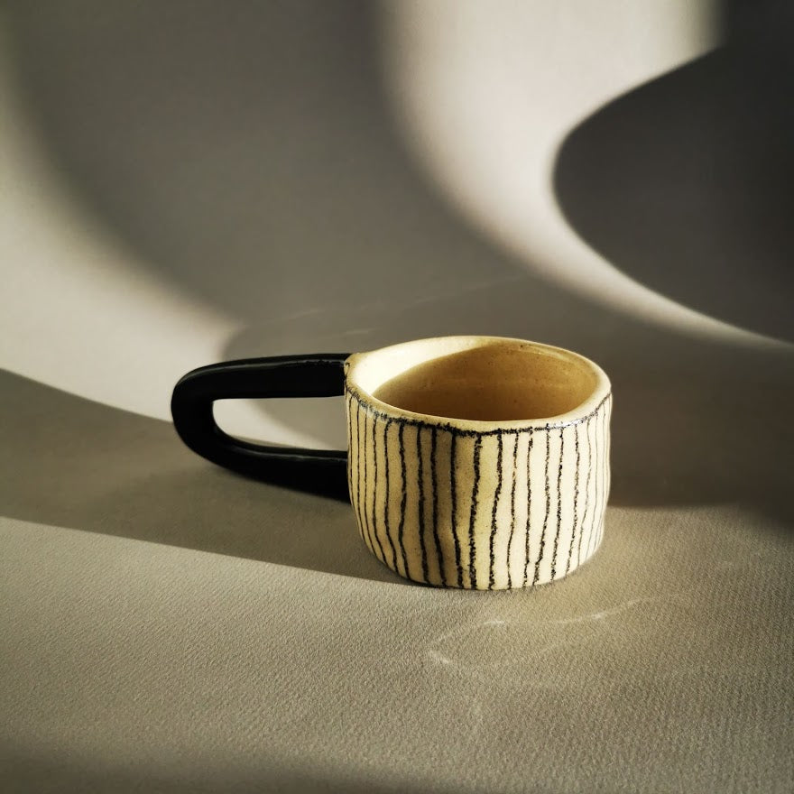 Magnifique tasse à grande anse noire, elle pourra vous servir à boire votre thé ou café et pourquoi pas comme objet de déco sur vos étagères.  La fonctionnalité des objets de Sabine Orlandini n’est pas immédiate ni définitive. Elle aime que ses objets soient utilisés pour une fonction à laquelle elle n’avais pas pensé. Ses pièces sont montées à la plaque. Elle utilise une terre de faïence blanche lisse ou chamottée, selon les effets et textures recherchés. Elle les engobe, les marque aux crayons oxydes et l